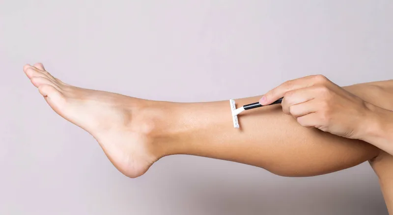 Persona depilandose la pierna